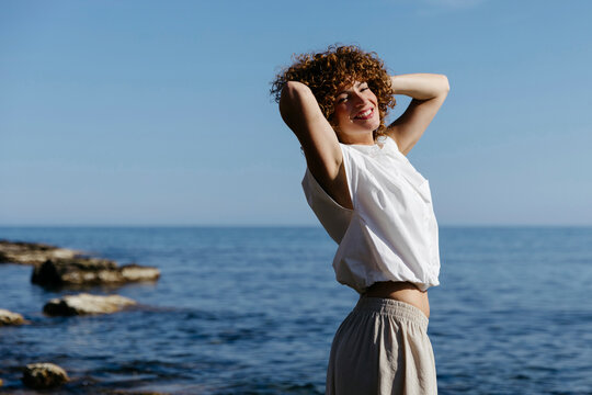 Woman with curly hair smiling with sea background