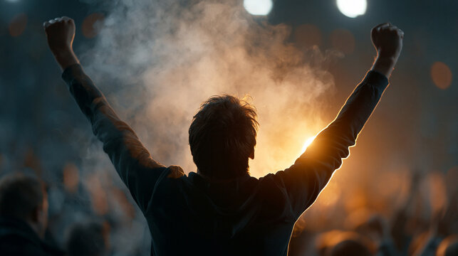 Silhouette of a man celebrating triumph at a crowded event.
