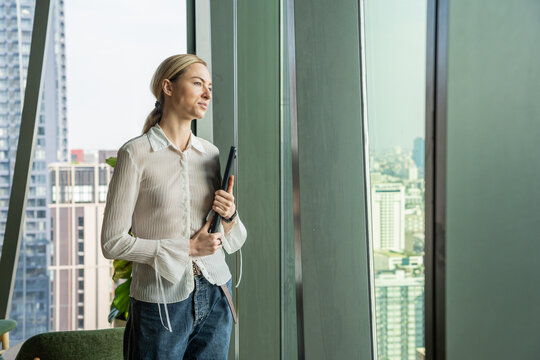 Business Woman Stands by Window Looking at City View