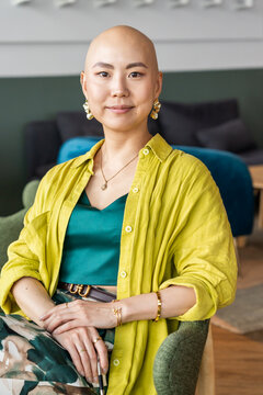 Bald Person With Earrings and Bright Clothing Sitting in Modern Area