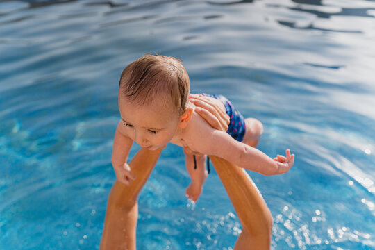 Baby learning to swim playing in blue pool