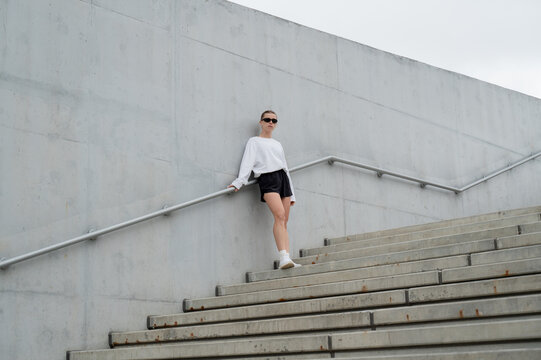 Athletic woman on urban steps against concrete architecture