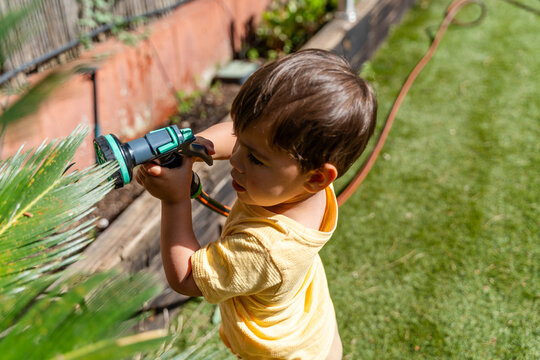 Child Aiming Hose At Plants