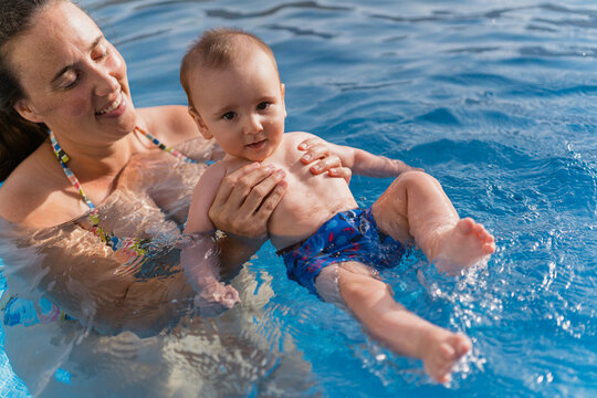 Mother teaching baby swimming in outdoor pool