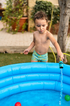 Boy filling inflatable pool with water in yard