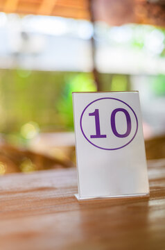 Table number 10 sign on wooden restaurant table with blurred background