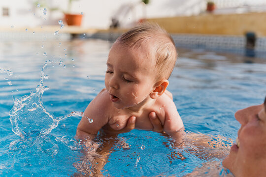 Baby learning to swim playing splashing in water