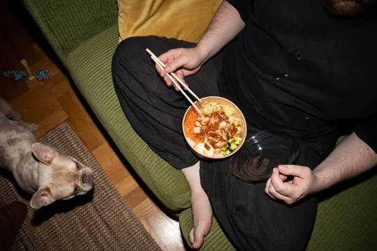Person Eating Takeout Meal While French Bulldog Watches
