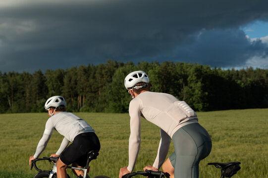 Cyclists riding toward dramatic storm clouds in countryside