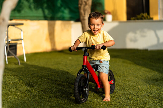 Happy toddler balancing on bike playing outdoors