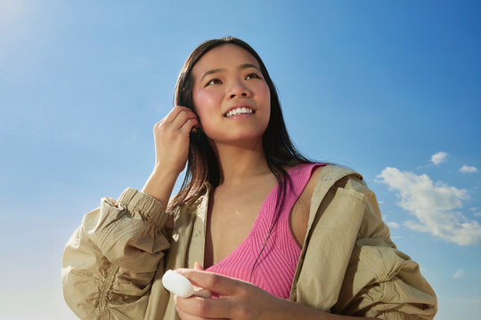 Woman Holding Earbud Case, Looking Up