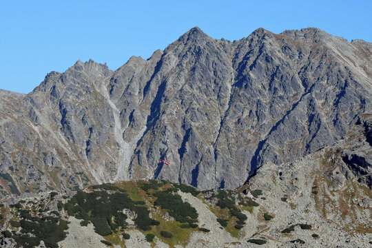 TOPR rescue helicopter flying against the steep walls of Świnica peak in Tatra Mountains