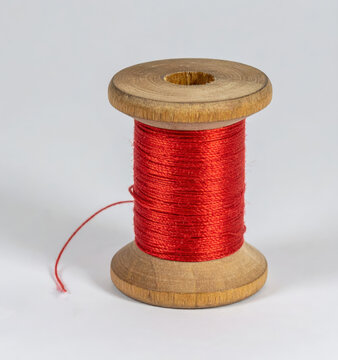 Wooden spool with red thread and sewing needle