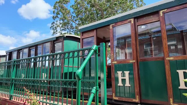 Hythe Hampshire England UK. 01.07.2026. Video.  Close-up view of a historic train car featuring polished wood trim, large windows, and a distinctive green paint scheme 