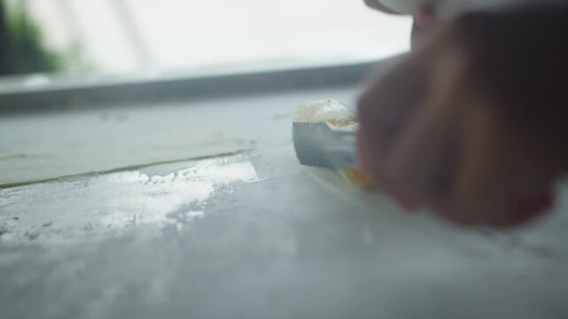 Close up of chef spreading mango ice cream on a frozen pan and carefully rolling it into neat ice cream rolls. Fresh homemade frozen dessert prepared by hand.