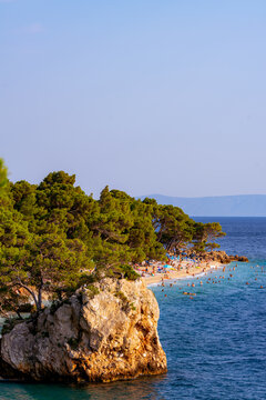 Vertical zoom shot of the famous Brela stone with crowded Punta Rata beach in the background