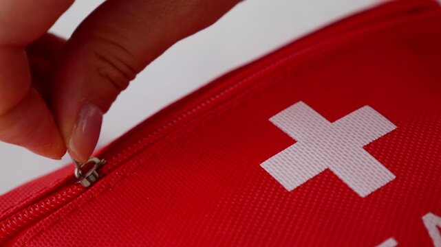 Close up of hands unzipping first aid kit for quick access to emergency supplies.