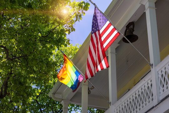 American flag and rainbow pride flag hanging on a historic Key West home porch