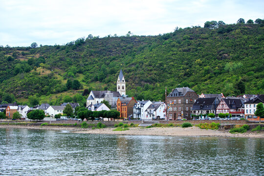 Scenic cruise along the Rhine River in Germany, with pretty waterside village of Kampbornhoffn and mountainous background