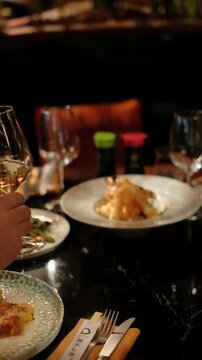 Close up of two hands holding wine glasses in a toast, surrounded by soft, glowing lights and a sense of warmth and elegance. The image evokes feelings of friendship, celebration, and holiday spirit