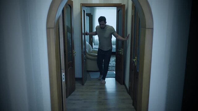 Drunk man staggers down hallway holding walls