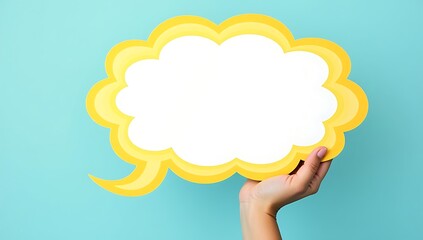 Obraz premium Hand Holding a Yellow Speech Bubble Against a Blue Background.