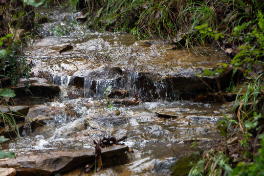 Water streams down the rocky mountain terrain after the rain