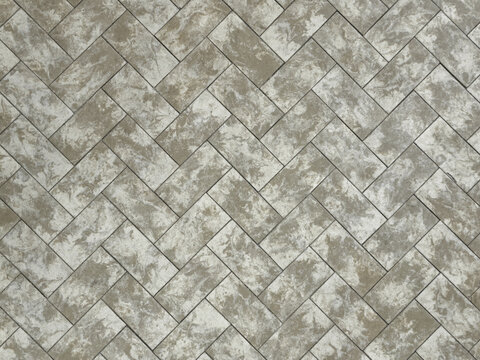 Herringbone paving slabs texture background. Interlocking concrete paver blocks pattern with marble effect. Grey and beige sidewalk brick surface backdrop.