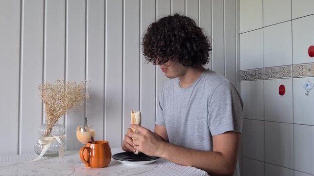 Person eats breakfast at a table in a bright room with simple decor and light color walls