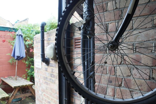 Close-up of a bicycle wheel and spokes in a rustic brick alleyway setting