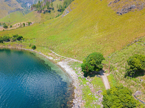 Aerial drone view of calm lakeside with greenery hills scenery near Toba Lake at Silalahi in Desa Binangara, Samosir, Sumatra Utara, Indonesia