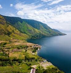 Fototapeta premium Aerial drone view of serene lakeside with Batak village scenery near Toba Lake at Silalahi in Desa Binangara, Samosir, Sumatra Utara, Indonesia