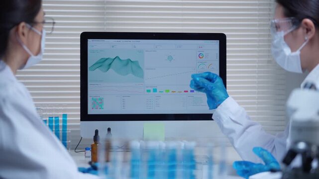 Female scientists analyzing research data on computer screen in modern medical laboratory for drug discovery and vaccine development