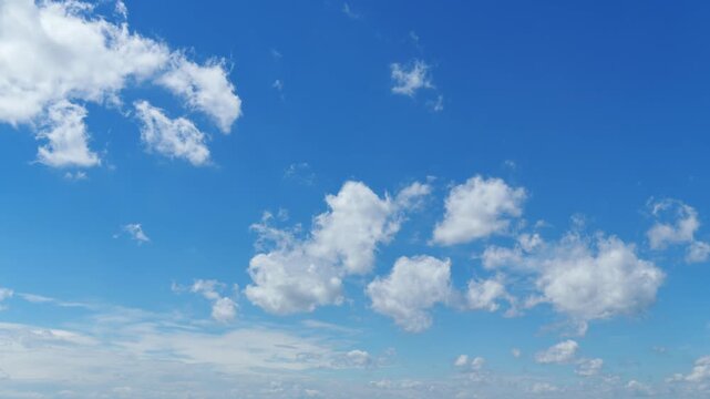 Time lapse video of fluffy white cumulus clouds drifting through a clear blue sky background. Beautiful atmospheric motion with bright daylight and sunny weather conditions