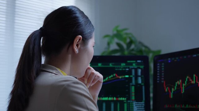Stressed stock market trader feeling desperate after a financial loss while watching cryptocurrency charts on a dual monitor setup