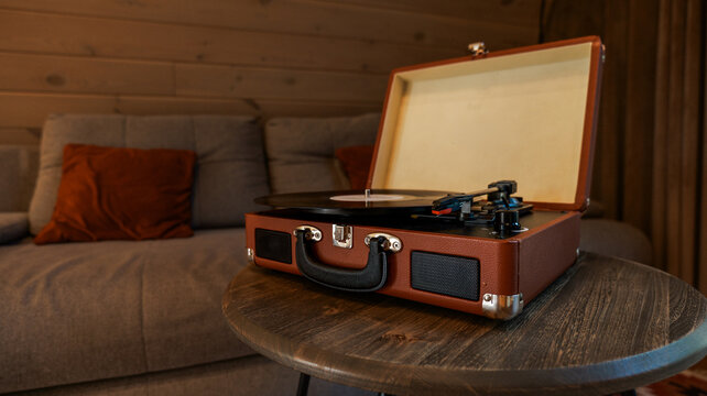 Vintage record player on a wooden table near a couch with a pillow