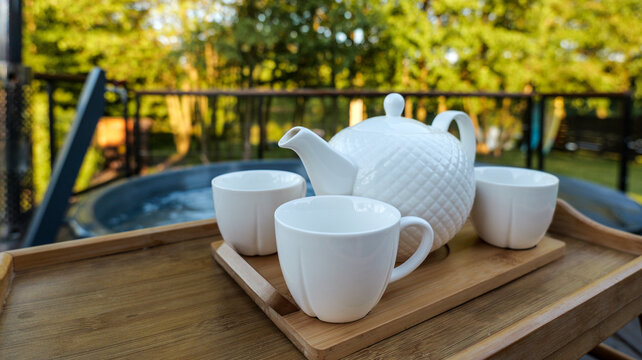 Relaxing tea break on a wooden tray beside a bubbling hot tub outdoors