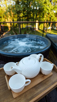 Relaxing outdoor hot tub experience with a tea set on a wooden tray