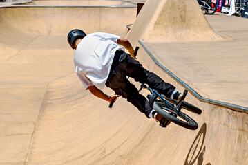 Obraz premium A young man practicing BMX and performing tricks at the skatepark