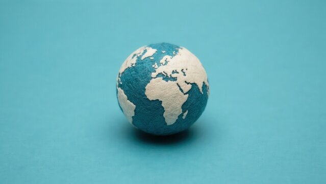 Small Handcrafted Globe on a Solid Blue Background Representing Earth and Sustainability
