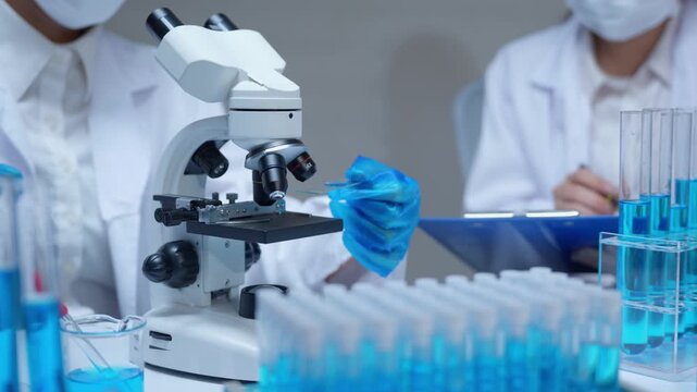 Scientist team working with a microscope and test tubes in a laboratory for research and development