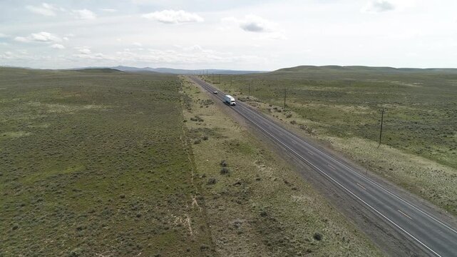 A road in the middle of a desert with a truck driving down it