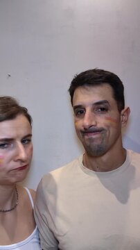 Sad Spanish Couple Football Fans with Flag Face Paint Crying After Match Loss, Disappointed Supporters Feeling Devastated Indoors, Dejected Emotion After Defeat. (187 caracteres)