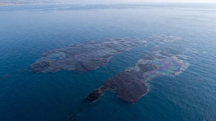Naklejka premium Aerial view of an oil spill in the ocean, environmental disaster with dark crude oil slick spreading on the sea surface