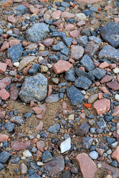 Texture of small multi colored pebbles and crushed stones on sand ground, natural gravel surface of river bank or coastal beach