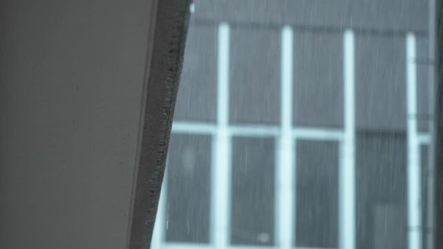 ビルを背景に降る雨とマンションの壁から滴る水