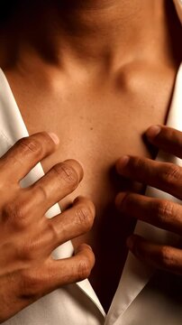 Close-up of a persons hands touching their chest and neck.