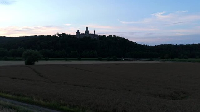 Marienburg Castle silhouette over golden wheat fields at sunset