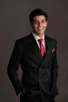 Portrait of a confident handsome young businessman in a black pinstripe suit and red tie smiling warmly
