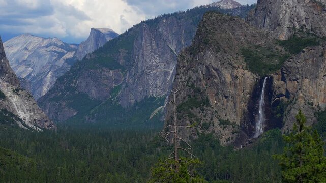 Static shot, locked camera. Yosemite Valley with a majestic waterfall flowing down the cliffs. Natural movement of cascade